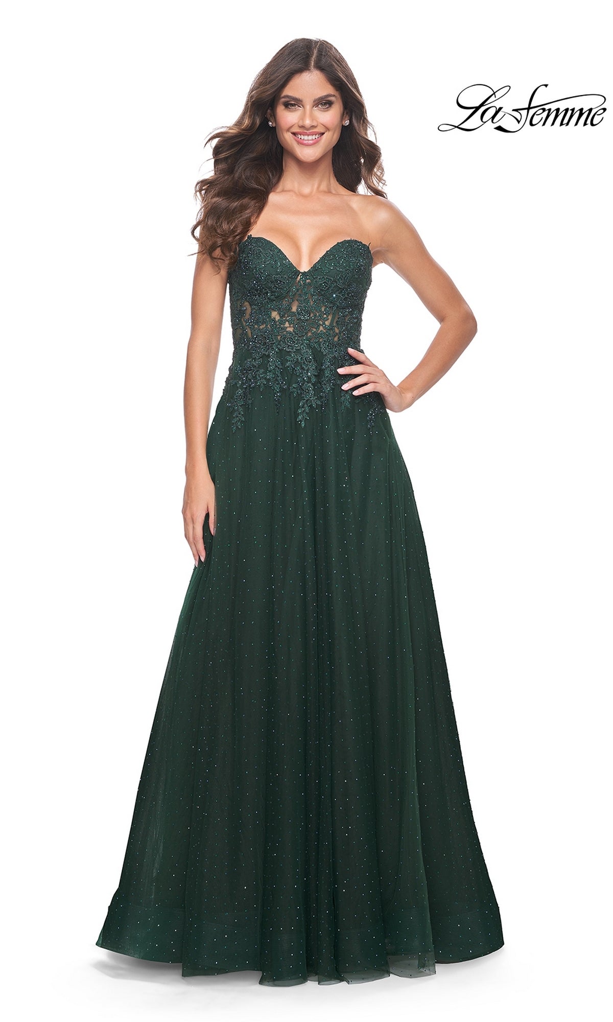 A woman smiles against a white background wearing the La Femme Sheer-Lace Long Beaded Prom Dress 32253, a strapless dark green gown with floral lace details and sparkling embellishments.